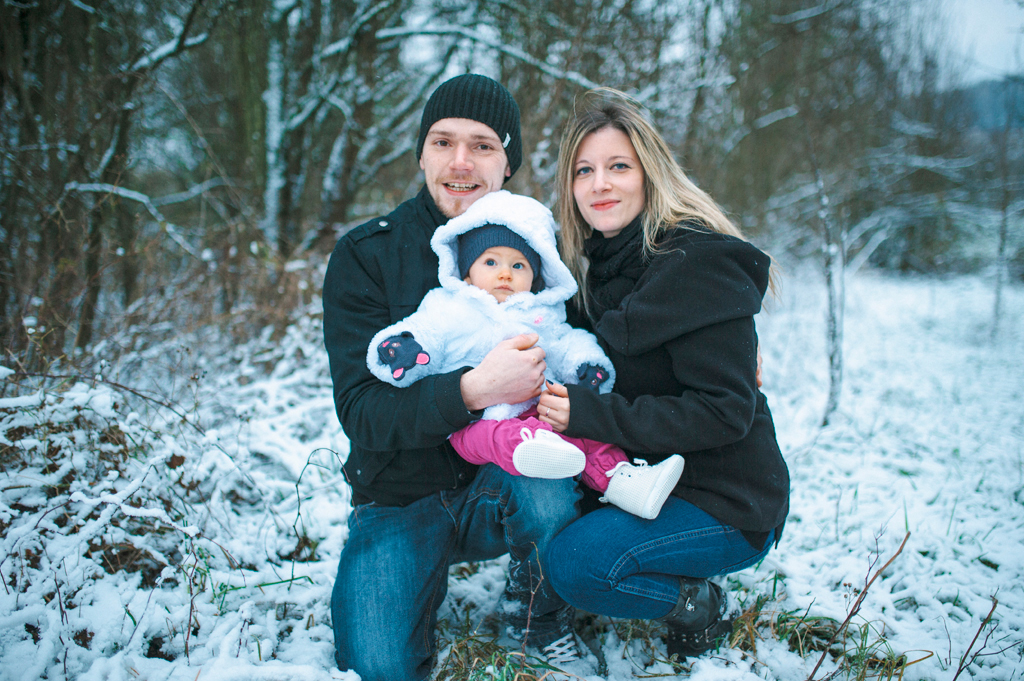 Séance famille Naomie, photo de famille accroupie dans la neige avec Naomie dans les bras