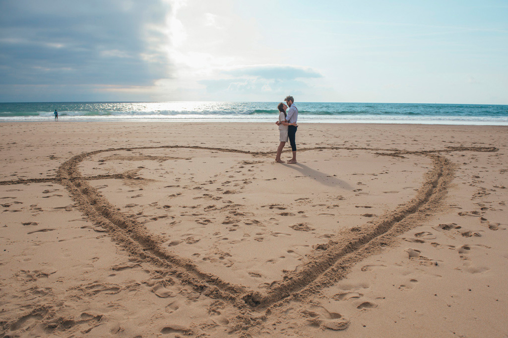 Mariage Ombeline et Albin, photo extérieure plage les mariés s'enlacent au milieu d'un coeur tracé dans le sable