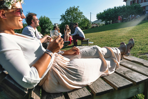 Mariage Ombeline et Albin, photo extérieure les invités sont assis sur des chaises longues en bois et boivent du champagne